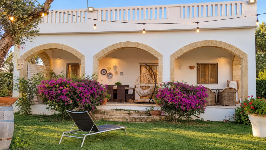 Facciata della casa al tramonto con la dondolo in vimini sul portico